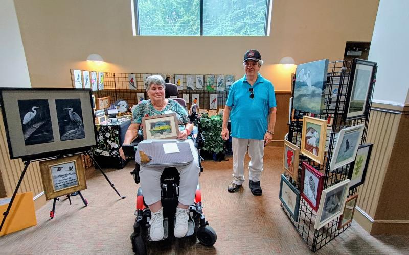 Megan Horn/The Clayton Tribune. Peggy Arnett, left, and Terry Arnett with “Leaf it to Me Artistic Creations” display their original creations at last weekend’s Painted Fern Festival of Art. Peggy has a unique talent for painting on leaves and preserves them by framing them.
