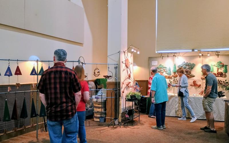 Megan Horn/The Clayton Tribune. Several people check out Gail Marsengill’s creations featuring copper creations at last weekend’s Painted Fern Art Festival.