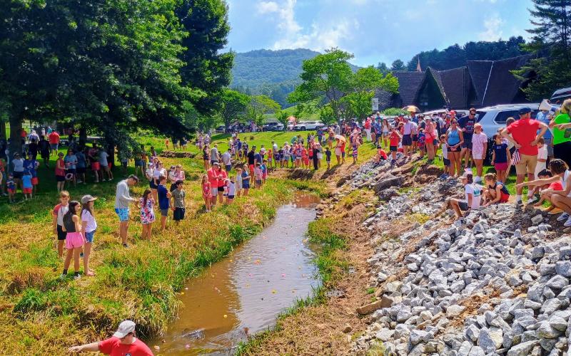Megan Horn/The Clayton Tribune. Visitors to Sky Valley eagerly watch as rubber ducks race down the creek to become the fastest duck in Sky Valley during Independence Day celebration events on Friday, July 3.
