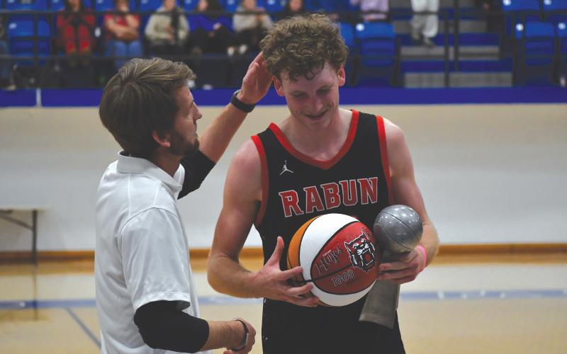Wesley Branch/The Clayton Tribune. Rabun County head boys basketball coach David Adcock (left) presents RCHS senior Hayes Free with a commemorative ball for scoring his 1,000th career point after the Wildcats’ win over Chesnee (S.C.) on Dec. 30. Free recently announced his commitment to Young Harris College.