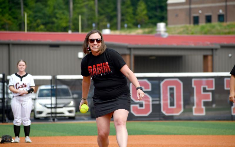 Wesley Branch/The Clayton Tribune. Rabun County High School principal Kelsey Thompson throws the ceremonial first pitch ahead of Rabun County’s 15-14 win over East Jackson on Aug. 3. Thompson, who graduated from RCHS in 2007, is in her first year as the high school’s principal.