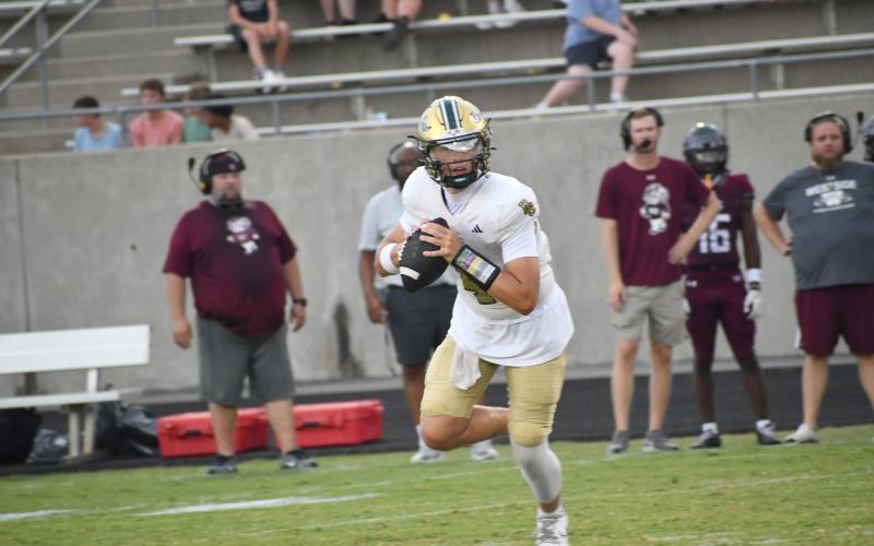 Wesley Branch/The Clayton Tribune. Rabun Gap quarterback Grayson Clary rolls to his right as he looks for an open receiver during Rabun Gap’s Aug. 14 scrimmage versus Westside (S.C.). Clary, who has 20 Division I offers, will make his first start as RGNS’ quarterback on Aug. 21 when the Eagles host Venice (Fla.) High School. Kickoff will be at 6 p.m