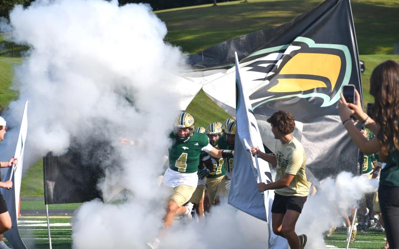 Wesley Branch/The Clayton Tribune. Rabun Gap, led by quarterback Grayson Clary, (center) runs through the Eagle banner onto the field ahead of Rabun Gap’s season-opener versus Venice on Aug. 21. The Eagles will face No. 17 Brownsburg in Indiana on Aug. 28.
