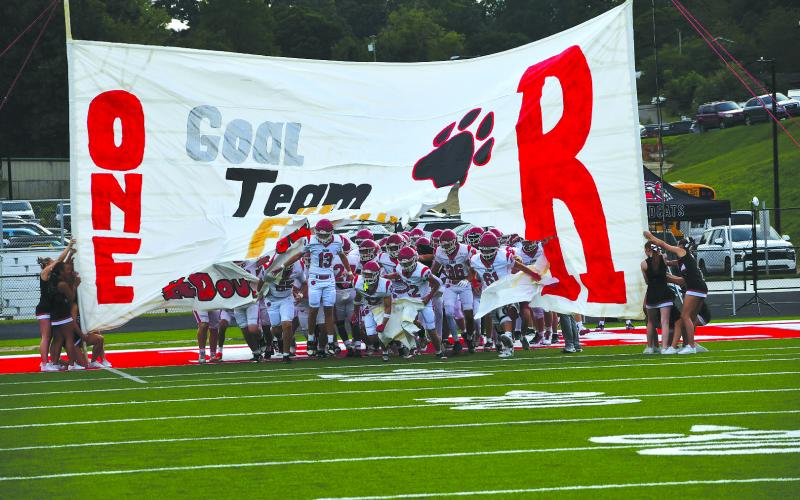Enoch Autry/The Clayton Tribune. Rabun County football players break through the cheerleaders’ handmade banner on Aug. 14 prior to the Wildcats’ scrimmage on the road against Franklin, N.C. RCHS kicks off its regular season at home on Aug. 28 versus the Tigers of Metter, led by former Wildcat coach and player Lee Shaw.