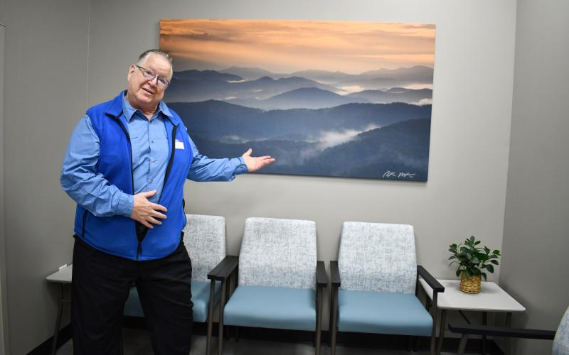 Megan Horn/The Clayton Tribune. Local photographer Peter McIntosh has 16 large pieces on display at MedLink Georgia Rabun Health Campus and hand-signed all of them. Here, he is pictured March 26 in front of his photograph capturing a view from Tennessee Rock Overlook at Black Rock Mountain State Park. McIntosh passed away on July 20.