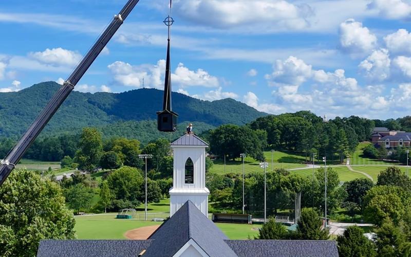 Photo courtesy Scott Poss.  A crane from TKS Installation and Sales of Warner Robins, Ga., lifts the new steeple and spire to the belfry tower of the new sanctuary of Rabun Gap Presbyterian Church. Chuck Lanier perches atop the tower to guide it in place. In the background is the Rabun Gap Nacoochee School, where the church first met in 1929.