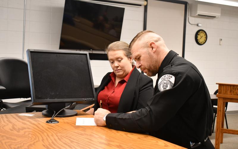 Megan Horn/The Clayton Tribune. Newly sworn-in Clayton Police Chief Kevin Marsteller, right, signs paperwork next to Rabun County Probate Judge Savannah Dixon after administering the Oath of Office to Marsteller on Thursday, Aug. 27, in the courtroom at Clayton City Hall.