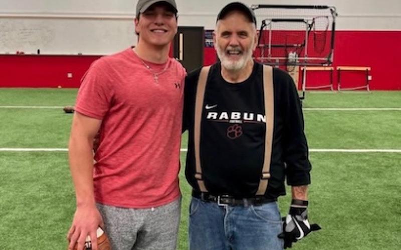 Photo via @gstockton14 on Instagram. Gunner Stockton (left) poses for a photo with George Bobo on Stockton’s signing day in December 2021. Stockton began training with Bobo at age 6 and now plays for his son and University of Georgia offensive coordinator Mike Bobo and with grandson Drew Bobo, Georgia’s starting center.