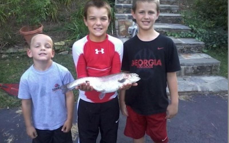 Photo courtesy of George Bobo.  A young Gunner Stockton (middle) stands with a young Drew Bobo (right) and Jake Bobo (left) boasting a fish they caught while fishing together as children. The three boys who have known each other and their families for many years, will begin Stockton and the elder Bobo’s final season of collegiate football on Sept. 5 when Georgia hosts Tennessee State.