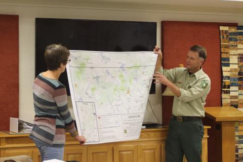 Megan Broome/The Clayton Tribune. Marie Dunkle, board president for Georgia ForestWatch, left, and Ryan Foote, district ranger for the Chattooga River Ranger District of the Chattahoochee-Oconee National Forest in Lakemont, hold up a map of National Forest System Land in Georgia potentially for sale. Foote points to the location of Rabun County, where approximately 1,229 acres of the roughly 3,841 acres is located. 