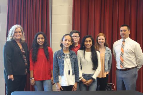 Megan Broome/The Clayton Tribune. Superintendent April Childers, left, Vanessa Balderas, Itzia Vasquez, Justin Cody, Melanie Mendoza, Roseanna Carver and assistant superintendent Jonathan Gibson attend the REACH signing ceremony in the Rabun County Band Room last Friday. 
