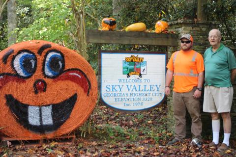 Cody English, left, Sky Valley public works employee, and Sky Valley Mayor Robert MacNair reveal Sky Valley's Fall decorations at the entrance to the city. The city has 13 hay bales that were painted by English and they stay out through the month of October. 