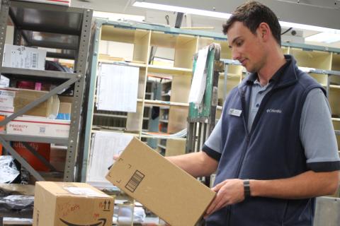 Megan Broome/The Clayton Tribune. Colby Nichols organizes packages for shipment at the Clayton Post Office on Monday. The Post Office saw a 14 percent increase in packages compared to the same time last year. 
