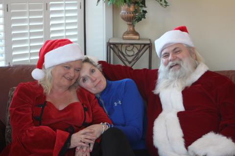 Megan Broome/The Clayton Tribune. Wanda Findley, middle, poses for a picture with her friends and neighbors MaryJane Phillips and Thomas Phillips, who travel around Georgia every year to portray Santa and Mrs. Claus. They give out presents to special needs and terminally ill children.