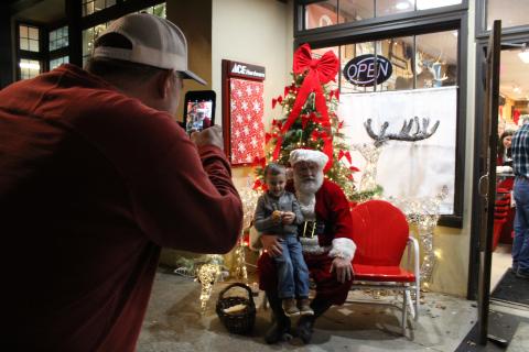 Rawlin Maxwell, 3, pays Santa Clause a visit while his grandfather Darren Dickerson snaps a picture during Christmas in Downtown Clayton