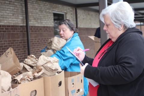 Megan Broome/The Clayton Tribune Elisa Tate, cafeteria worker at Rabun County Schools, left, and Reneta “Skeet” Hollifield, cafeteria manager at Rabun County Primary School (RCPS), pass out sack lunch meals at RCPS on Monday so that students have food to eat while school is closed due to COVID-19 concerns. 
