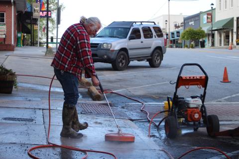 Megan Broome/The Clayton Tribune. Rob Hawsey with the streets department pressure washes the sidewalk on Main Street Tuesday. 