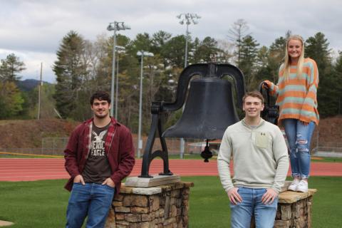 Megan Broome/The Clayton Tribune.Rabun County High School’s top three students stand by the large bell on the football field that is rung at graduation each year. Mason Sprinkle, left, is Historian, Will Hightower is Salutatorian and Ali Ramey is Valedictorian for the 2019-2020 academic year.