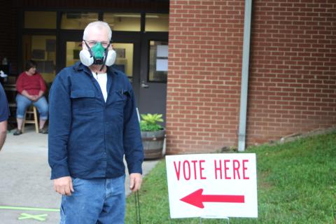 Megan Broome/The Clayton Tribune. Charles Wilkins wears a respirator mask as he participates in early voting at the Rabun County Board of Elections Office Monday. Voters are required to stand six feet apart as one person at a time goes into the building to cast their ballot. These areas are marked with tape along the sidewalk. This is part of COVID-19 precautions mandated by the state of Georgia.