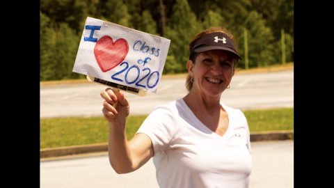 Photo courtesy Rabun County Schools. Jane Johnston, RCHS math teacher, shows her support for the Class of 2020. Rabun County High School seniors picked up their senior packets of their cap, gown, and care package last Friday. Family, friends, school officials and community members show their love to the Class of 2020 by decorating cars, holding up signs and waving and cheering as cars go by. 