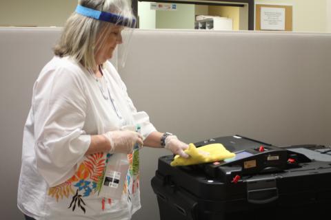 Megan Broome/The Clayton Tribune. Poll Worker Pat Hopper disinfects the entire voting area at the Board of Elections Office after each person finishes casting their ballot. Only one voter at a time is allowed inside the building for early voting as part of COVID-19 contact precautions. 