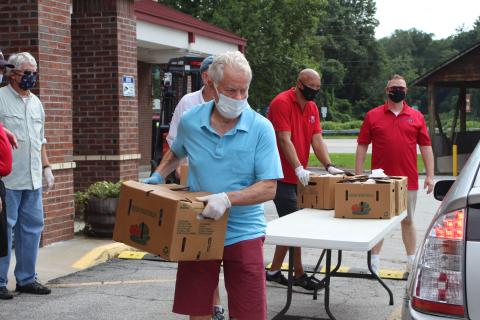 Megan Broome/The Clayton Tribune. Rotarians Ray Pagano, Matt Mitchum, James Brim and Tony Penrose help load food into vehicles. 