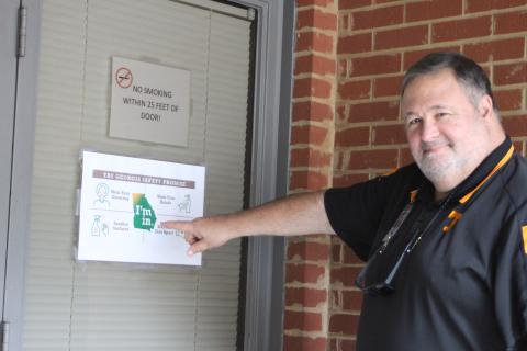 Megan Broome/The Clayton Tribune. Chuck Leming, technician for Dominion Voting Systems, points to a sign posted by the Rabun County Board of Commissioners Office that encourages voters to wear masks and maintain social distancing while at the polls. 