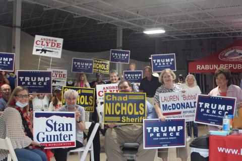 Megan Broome/The Clayton Tribune. Members of the Rabun County Republican Party and community patrons hold up campaign signs at the grand opening of their campaign headquarters last Saturday. 