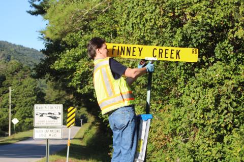  Megan Broome/The Clayton Tribune. Keith Yunger, sign technician for the Rabun County mapping department, replaces one of the road name signs located on Warwoman Rd. that was stolen on Labor Day weekend. A total of 80 signs were reported stolen, along with one stop sign and seven stop signs damaged. Yunger installs all of the road signs in the county. 