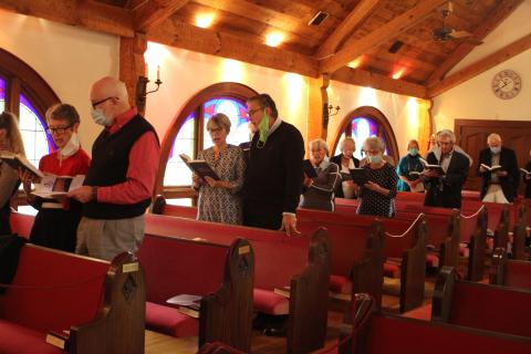 Megan Broome/The Clayton Tribune. The congregation stands and sings hymnals at a church service and special 40th Anniversary celebration of the Tom McClure Memorial Chapel in Sky Valley Sunday. 