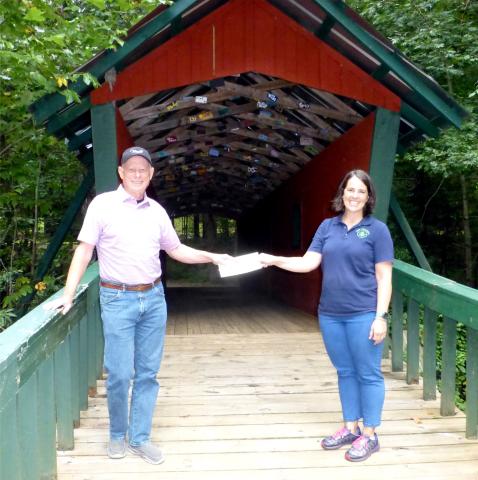Submitted photo. Lake Burton Civic Association President Mike Hammer, left, presents a check to Jeanie Cook Camp Evergreen.