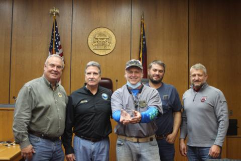 Megan Broome/The Clayton Tribune. Commissioners Kent Woerner, left, chairman Gregg James, Will Nichols, and County Administrator Darrin Giles present Stephen Arbitter (center) with an award for his 8 years of service as a commissioner at last Tuesday’s meeting. It was Arbitter’s last meeting before vacating his seat. 