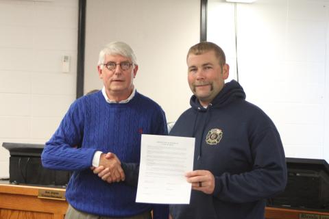 Megan Broome/The Clayton Tribune. Clayton Mayor Jordan Green and Clayton city council members signed a resolution to proclaim that whatever day on which the city of Clayton Christmas parade takes place is hereby declared “Carl Butler Day.” Butler, left, shakes hands with Jordan Green after the city adopted the resolution at Tuesday’s council meeting. 