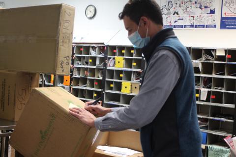 Megan Broome/The Clayton Tribune. Colby Nichols, acting supervisor at the Clayton Post Office, sorts packages that the USPS is receiving in large volumes during the holiday season. 