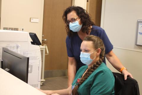 Megan Broome/The Clayton Tribune. Mandy Hopkins, director of performance improvement and care coordination at Mountain Lakes Medical Center (MLMC), left, and Hope Brown, patient care technician in the MLMC emergency department, review a patient's chart in the emergency department at Mountain Lakes Medical Center. 
