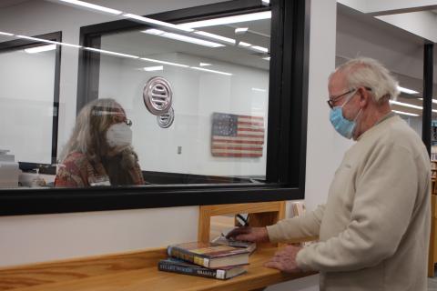 Megan Broome/The Clayton Tribune. Circulation Clerk Peggie Wilcox, left, checks out a library patron at the new circulation counter on Tuesday. 