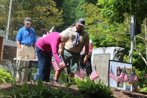 Megan Broome/The Clayton Tribune. Wilma Hoilman places a flag to honor the memory of a veteran close to her who has passed away at Monday’s Memorial Day ceremony. Also pictured are Col. (Ret.) Guy Gober, who was the guest speaker, left, and Eagle Scout Dominic Cross. 