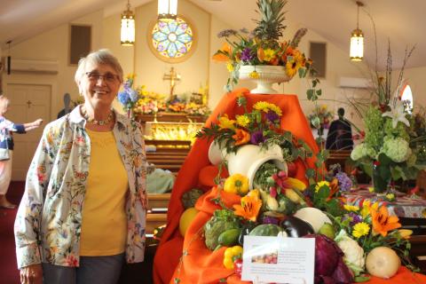 Megan Broome/The Clayton TribunePeggy Melton stands in front of a floral arrangement . depicting “God’s Bounty” at the 14th annual Flower Festival at St. James Episcopal Church on Saturday.  The theme was “God’s Creation: Behold, I make all things new” and floral arrangements were created to represent and celebrate God’s creations. 