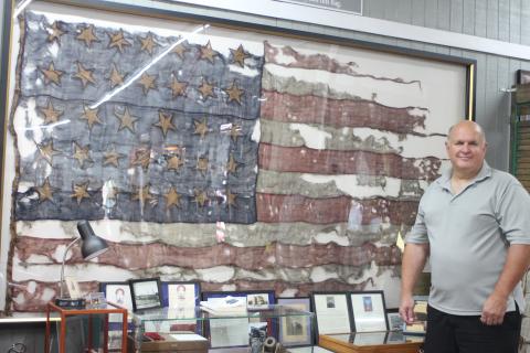 Megan Broome/The Clayton Tribune. Bob Matis, owner of Civil War Corner Antiques in Dillard, owns a United States flag used in the Civil War in the Battle of Cold Harbor on June 3, 1864. It is displayed in his shop along with a display. The flag has 34 stars and two stripes are missing after being torn off in battle. 