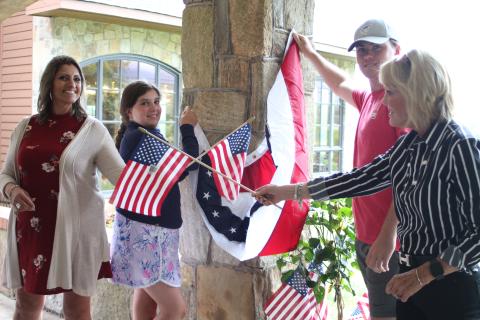 Megan Broome/The Clayton Tribune. Jo Flores, left, Blaire Cross, Dillard Cross and Louise Dillard, owner of The Dillard House, decorate The Rock House at the Dillard House in Dillard on Tuesday to prepare for upcoming Fourth of July festivities. The Dillard House will host a BBQ and live music on Saturday and Sunday. 