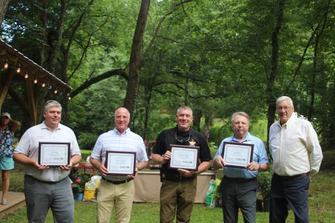 Megan Broome/The Clayton Tribune. Leadership Rabun participants Josh Allen with Habersham EMC, left, Brent Edwards with Georgia Power, Chad Nichols with the Rabun County Sheriff’s Office and Sam Burns of the Rabun County Republican Party are handed their certificates of completion of the program by Tony Allred, former president of the Rabun County Chamber of Commerce at the Chamber’s after-hours event in Lakemont last month.