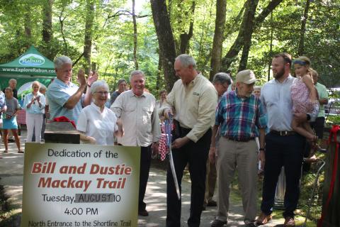 Megan Broome/The Clayton Tribune. The North Entrance to the Tallulah Falls Shortline Trail was dedicated to Bill and Dustie Mackay, who have maintained the trail for 25 years, at a ceremony on Tuesday. Community members, officials and state representatives cut the ribbon: Rep. Stan Gunter, left, Dustie Mackay, Wallace Bruce, Rick Story, director of development for Rabun County, Bill Mackay and State Sen. Bo Hatchett with daughter Hallie. 