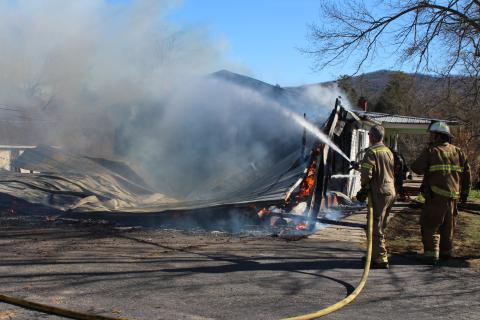 Megan Broome/The Clayton Tribune. Firefighters work to douse the remaining flames at a structure on Wolffork Church Road in Rabun Gap.