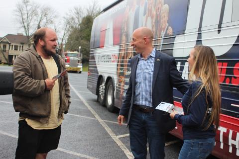 Megan Broome/The Clayton Tribune. U.S. Senate Candidate Josh Clark, center, and Chelsey Clark greet local Justin Stewart at a meet-and-greet at the Clarks’ “Liberty Bus” in Rabun County March 18. 