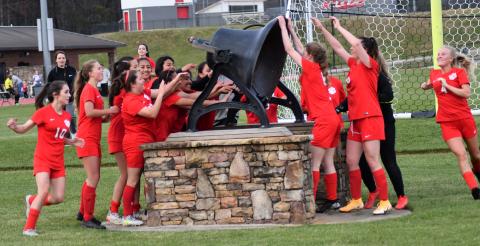 Enoch Autry/The Clayton Tribune. A smiling group of Ladycats ring the bell at the stadium after a 6-0 victory over the Lady Blue Devils.