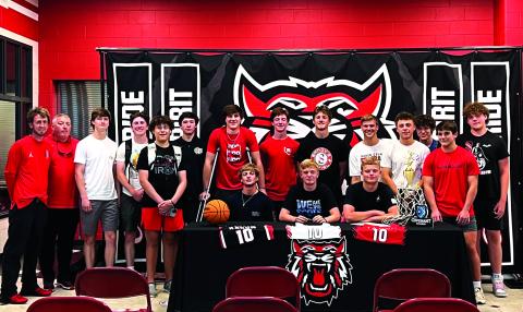 Submitted photo. Surrounded by his teammates, Rabun County senior Gus Hood (seated, center) signs with Covenant College after a solid high school career as a point guard. Hood averaged 13 points a game as a senior.