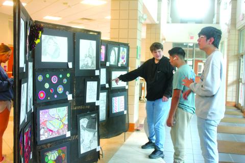 Megan Broome/The Clayton Tribune. Seniors Kane Collins, Ishy Duran and George Juarez browse the Rabun County High School Student Art Show held in the Fine Arts Building May 13. The show featured artwork from students in grades 9-12. 