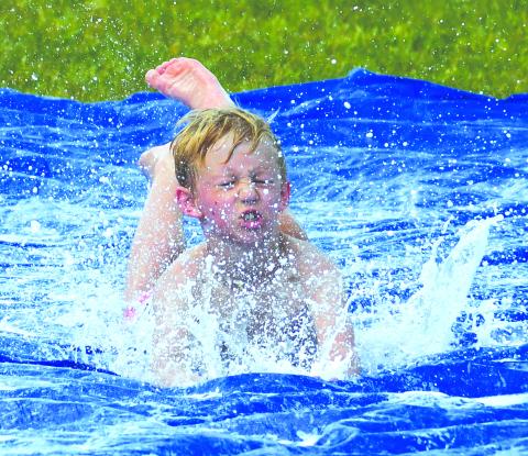Enoch Autry/The Clayton Tribune. With some of the hottest days this year statewide, Rabun County outdoor summer youth camps have been challenged in finding ways to keep participants cool. Here, Cowen Gilbert, does a head-first slide on a tarp soaked with water and dish detergent during the last day of the Wildcat Baseball Camp on June 16. 
