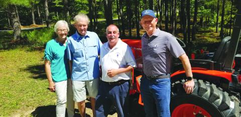 Submitted photo. Event organizer Kathy Booker, donor Steve Raebel, Victory Home Director Mark Beach, and donor Mike Hammer stand beside the new tractor that was purchased for Victory Home. 