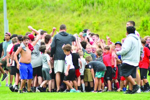 Enoch Autry/The Çlayton Tribune. With RCHS head coach Michael Davis (center) leading the group, the football campers react to an evening of fun on the field.